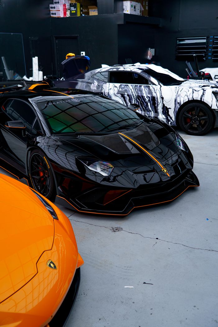services-01 Black and orange luxury sports cars in a sleek, urban garage setting.